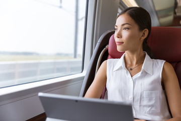Asian woman traveling using laptop in train. Businesswoman pensive looking out the window while...
