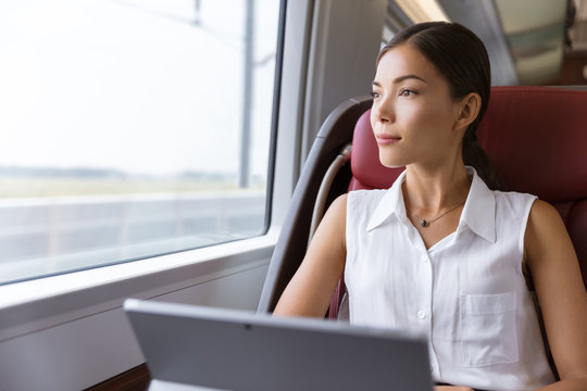 Asian woman traveling using laptop in train. Businesswoman pensive looking out the window while working on computer on travel commute to work.