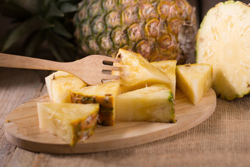 Pineapple slices and pineapple shelled Asian-style on the old wooden background. Tropical fruit concept