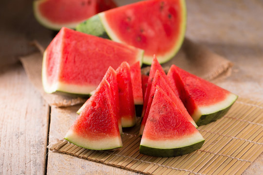 watermelon and watermelon pieces in a wooden background