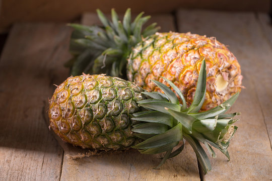 Pineapple slices and pineapple shelled Asian-style on the old wooden background. Tropical fruit concept
