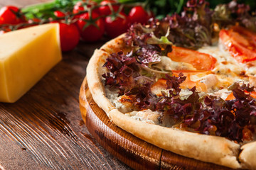 Tasty appetizing pizza served with ingredients on wooden rustic table, close up view. Italian traditional food.