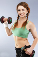 Smiling woman  with  old dumbbells in hands looks  in camera 