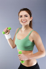 Fototapeta na wymiar Green dumbbells in hands of fitness young woman. Sport team