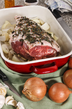raw leg of lamb with marinade in a pan