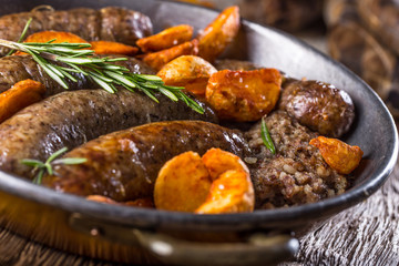 Sausages.Roasted pork sausage in a pan with potatoes and rosemary.