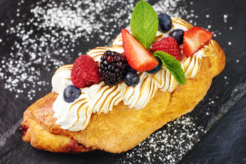 Close-up of cake with fresh berries and whipped egg whites on graphite board. 