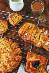 Vertical top view of assorted pastry with coffee and milk. Breakfast with pies, buns, brioches and cake. 