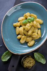 Italian potato gnocchi with basil pesto sauce on a turquoise plate, closeup, elevated view