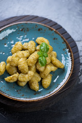 Potato gnocchi with basil pesto and fresh green basil leaves, selective focus