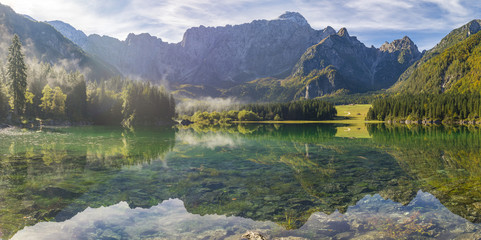 Beautiful, sunny and foggy morning on the alpine lake in the julian alps in italy