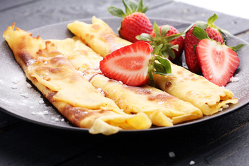 Crepes with jam, strawberries and sugar powder. Homemade pancakes, delicious breakfast