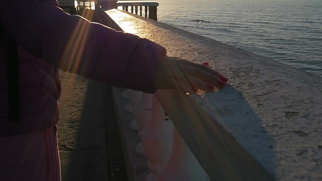 A beautiful young girl walks, touches stone parapet to sea. Pink clothes, spring time, Slow motion. Close-up shot