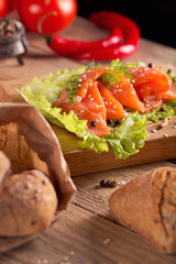 Slices of smoked salmon with dill, chili pepper, tomatoes and bread