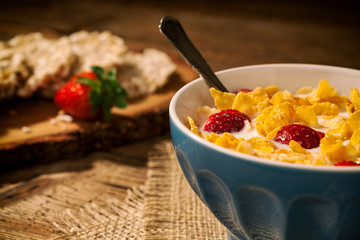 Closeup of a continental breakfast with cornflakes and strawberries in a cup of milk
