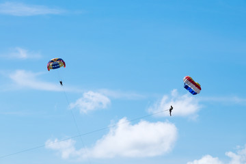 Parasailing against a blue sky and cloud.