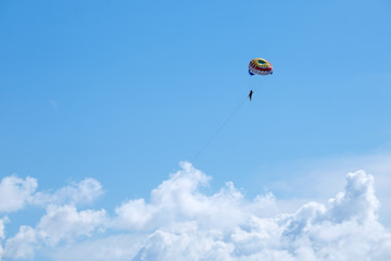 Parasailing against a blue sky and cloud.