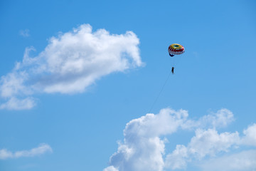 Fototapeta na wymiar Parasailing against a blue sky and cloud.