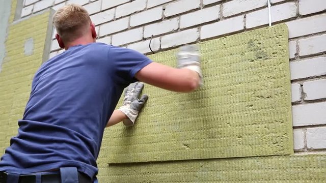 construction worker insulating house facade with mineral rock wool