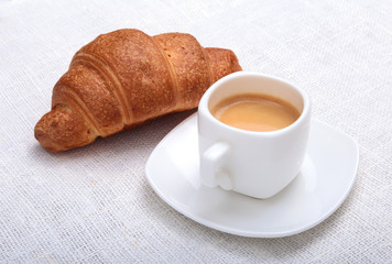 Crispy fresh croissants and cup of coffee espresso on a white background, morning breakfast, selective focus