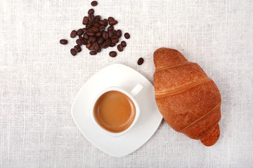 Crispy fresh croissants and cup of coffee espresso on a white background, morning breakfast, selective focus