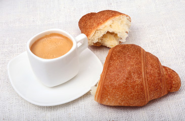 Crispy fresh croissants and cup of coffee espresso on a white background, morning breakfast, selective focus