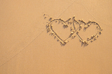 Two hearts drawn in the sand at the beach.