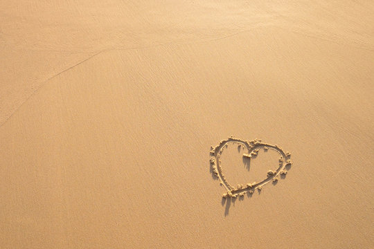 Heart drawn in the sand. Beach background.