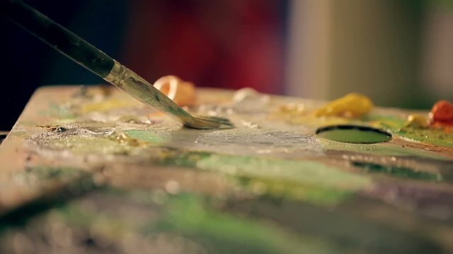 The artist mixes oil paint on a palette close up