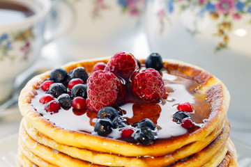 Pancakes with red and blue berries and honey, high key