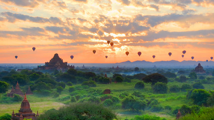 Bagan, Myanmar - sunrise over the many ancient pagodas with hot air balloons passing by