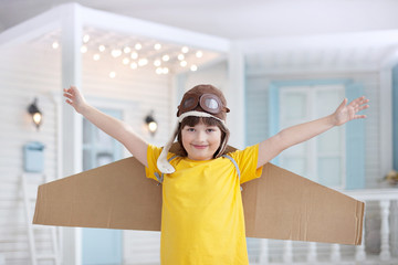 Happy boy with cardboard boxes of wings in home dream of flying