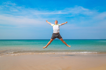 Fototapeta na wymiar Happy tourist man jumping in a tropical beach