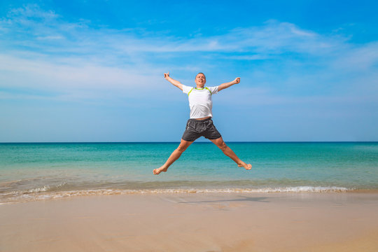 Happy tourist man jumping in a tropical beach