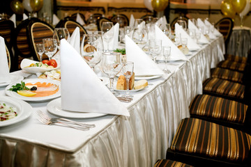 Table setting. Table served for wedding banquet, close up view. White napkin on a white empty plate on a dining table