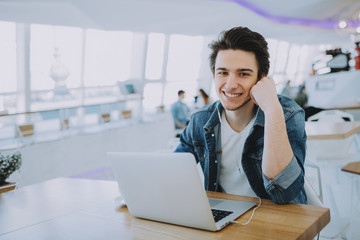 Young man working on a macbook or laptop in cafe