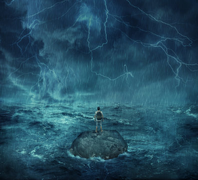 Lost man standing abandoned on a rock island in middle of the ocean, in a stormy night with lightnings in the sky. Looking for help, try to survive. Adventure, journey and hard determination concept.