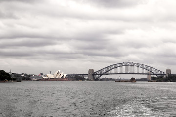 Naklejka premium Skyline von Sydney mit Opera House und Harbour Bridge an einem bewölkten Tag.