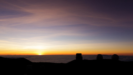 Sunset on the summit of Mauna Kea, Big Island, Hawaii: Astronomical observatories in front of a beautifully colored sky.