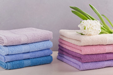 Obraz na płótnie Canvas Two stacks of colorful bath towels with hyacinth flower on light background.