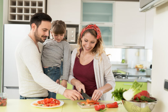 Happy young family preparing lunch in the kitchen
