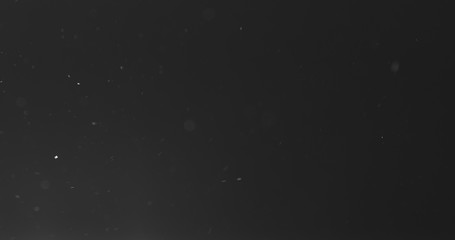 dust particles fast moving over black background from left, 4k photo
