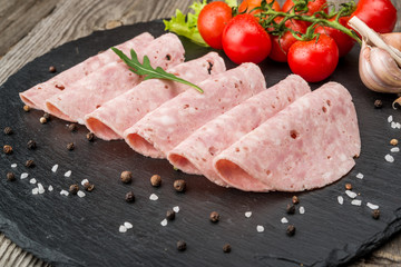 Cut sausage from ham on a wooden background