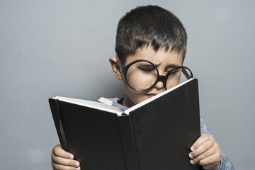 Preschooler, Boy with giant glasses reading a book with funny and varied gestures