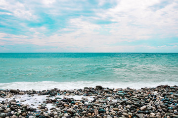 Beach with pebbles, sea with waves and sea foam.