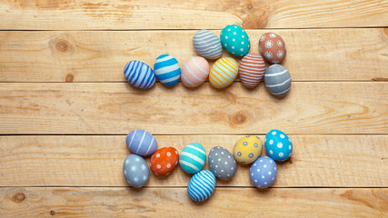 Obraz na płótnie Canvas Colorful handamde easter eggs on wooden board background with space. Flat lay style