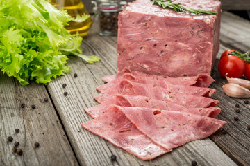 Cut sausage from ham on a wooden background