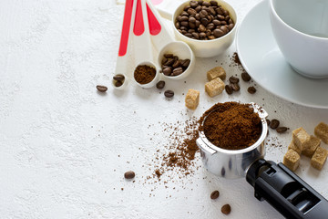 Ingredients for coffee: ground coffee in the horn of the coffee machine, sugar and a cup. Top view with copy space