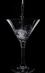 A glass with vermouth and ice cube on a black background