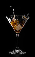 A glass with vermouth and ice cube on a black background
